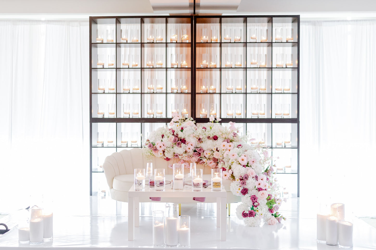 Decorative setup with flowers and candles in a room with a glass partition.