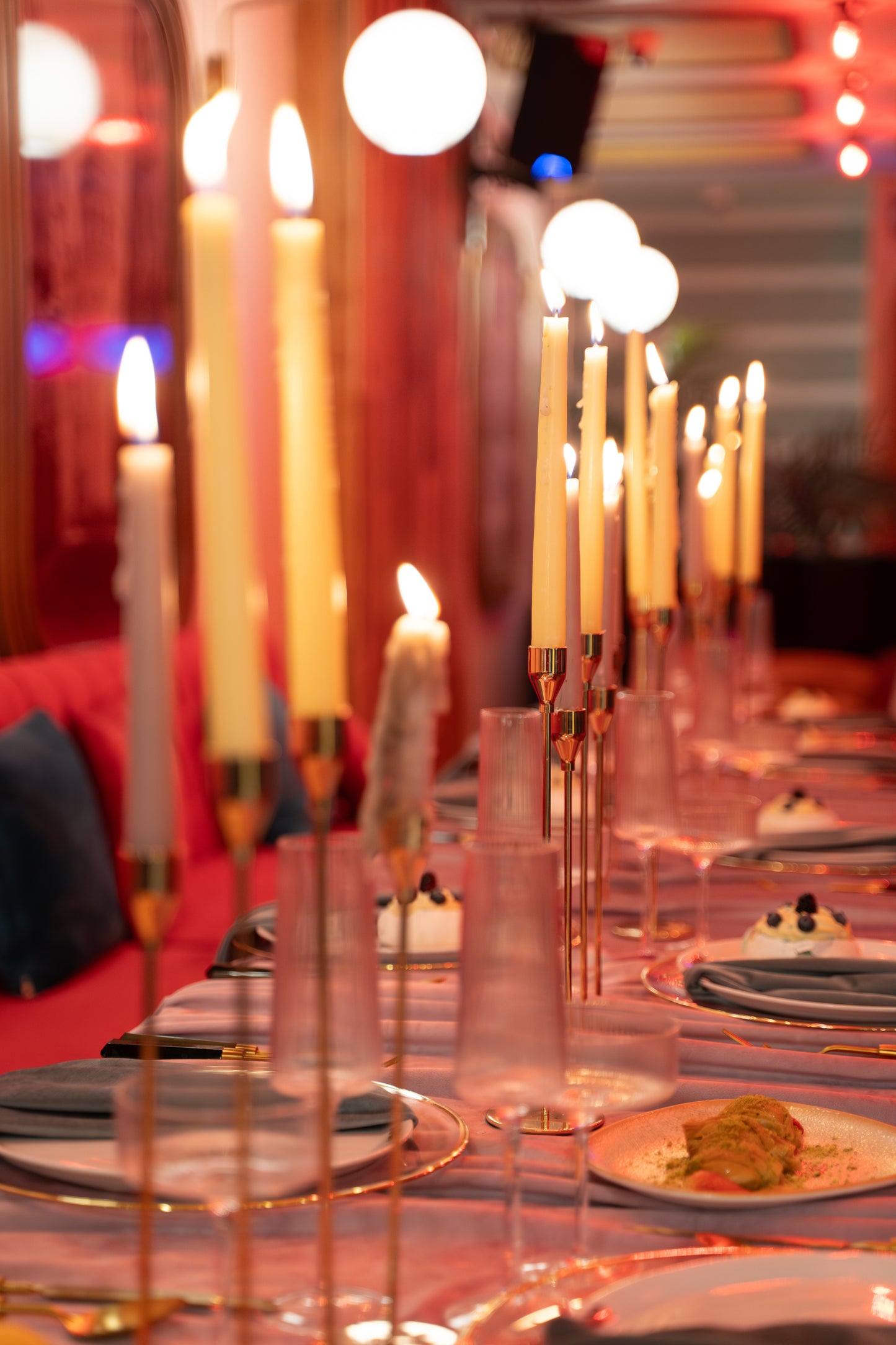 Decorative table setting with candles and plates in a warm, ambient setting.