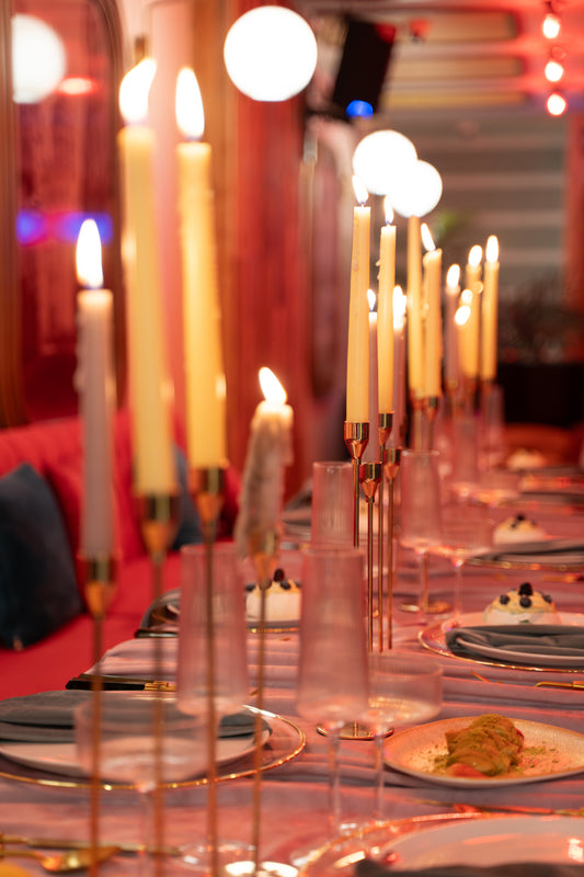 Decorative table setting with candles and plates in a warm, ambient setting.