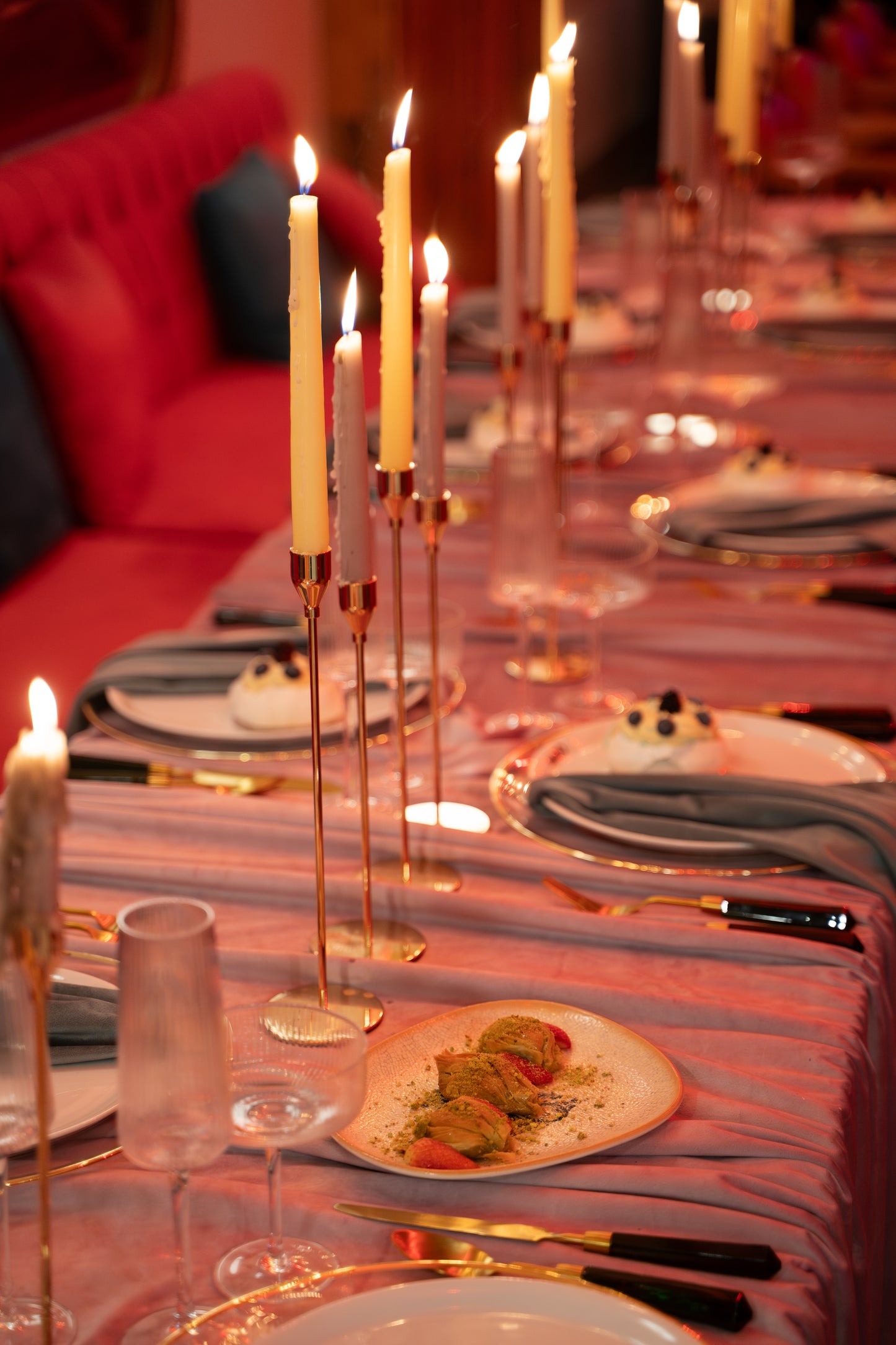 Dining table set with plates, candles, and cutlery in a formal setting.