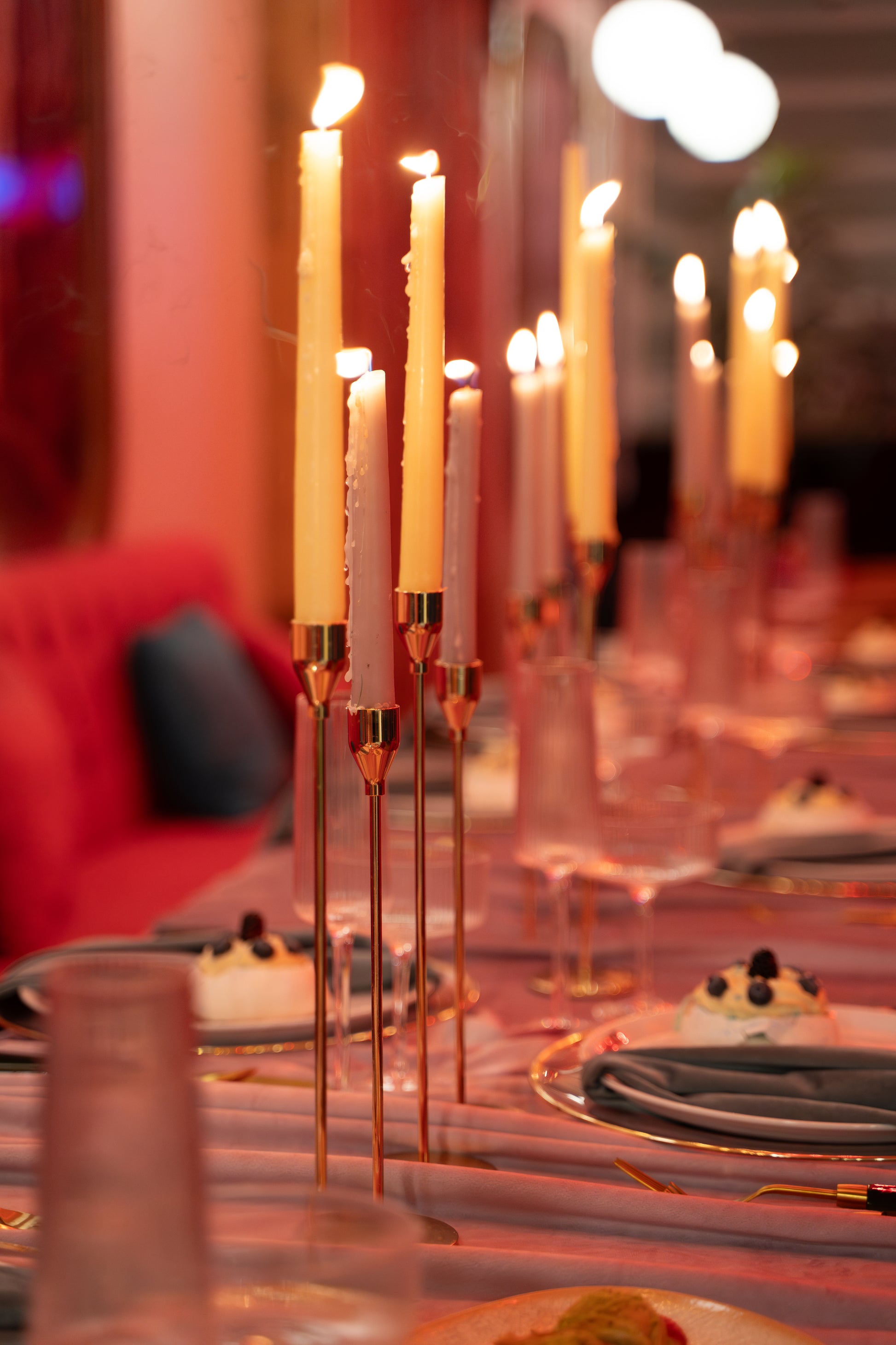 Decorative table setting with lit candles and small desserts on a blurred background tapper candle