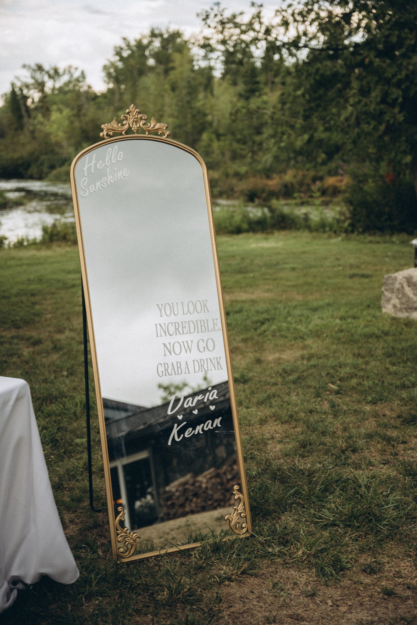 Decorative mirror with text and gold frame outdoors on grass