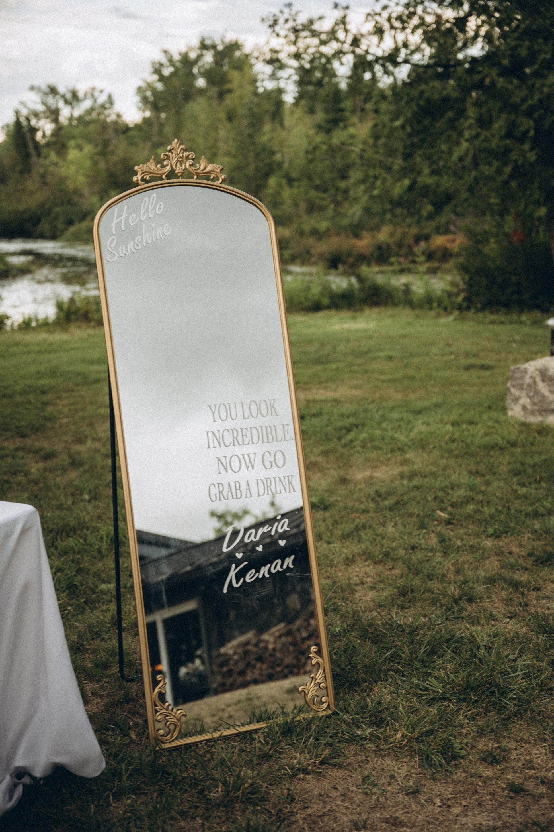Decorative mirror with text and gold frame outdoors on grass